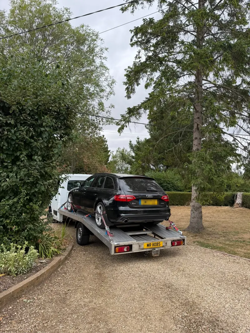 Black Audi A4 Avant on the recovery truck on a gravel driveway