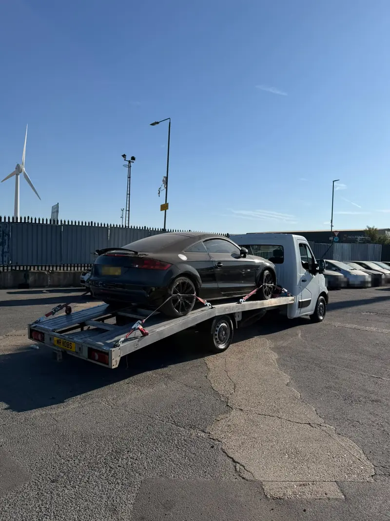 Black Audi TT secured on the flatbed in a vehicle storage yard