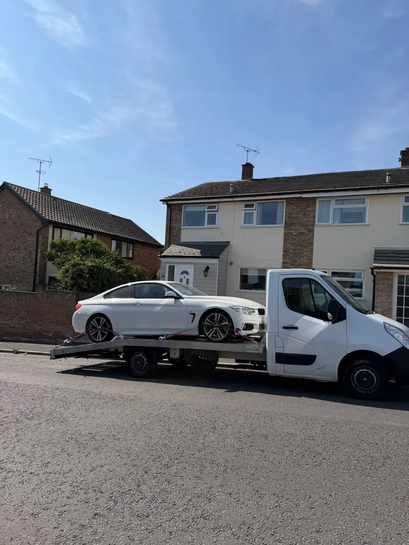 White BMW 4 Series on the recovery truck parked outside a house