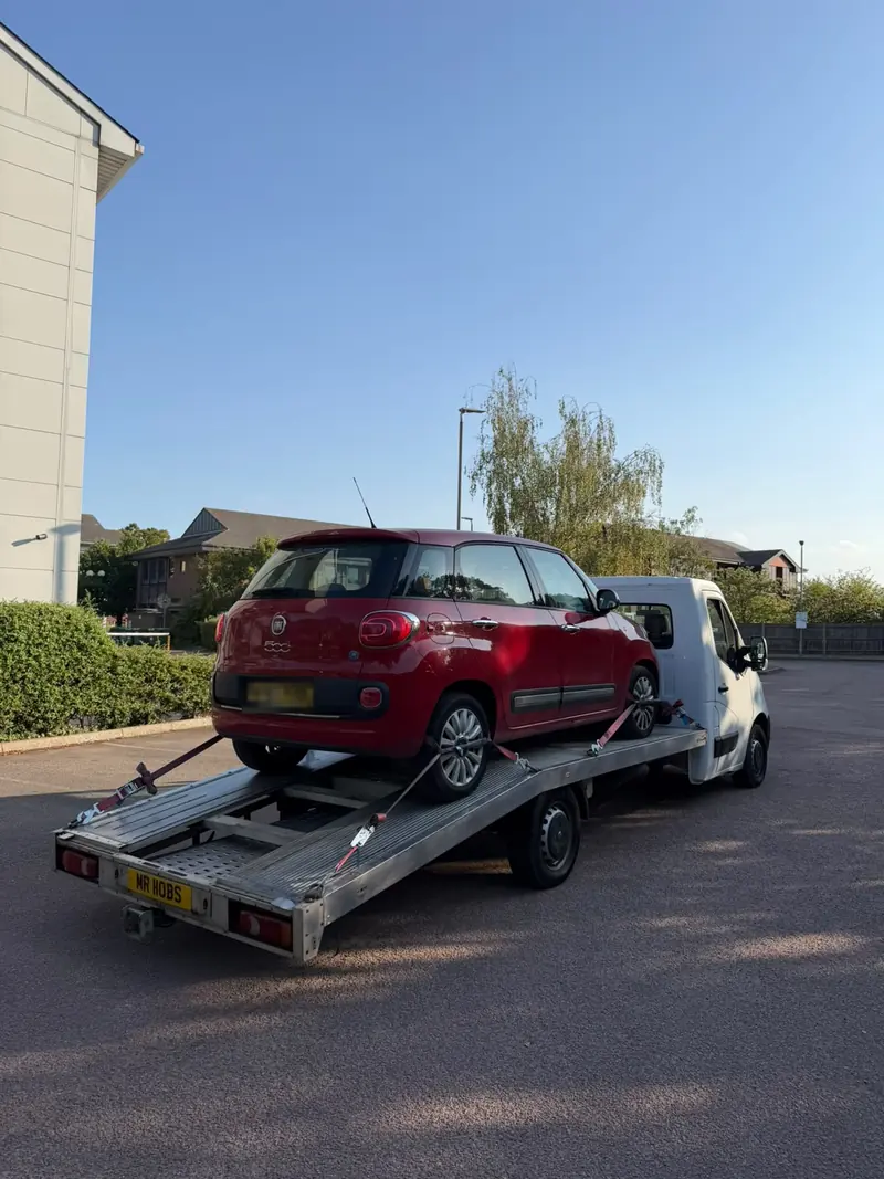 Red Fiat 500L strapped to the recovery truck in a car park