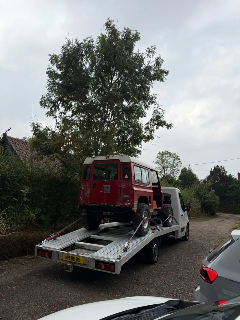 Red Land Rover Defender 90 secured on the flatbed recovery truck